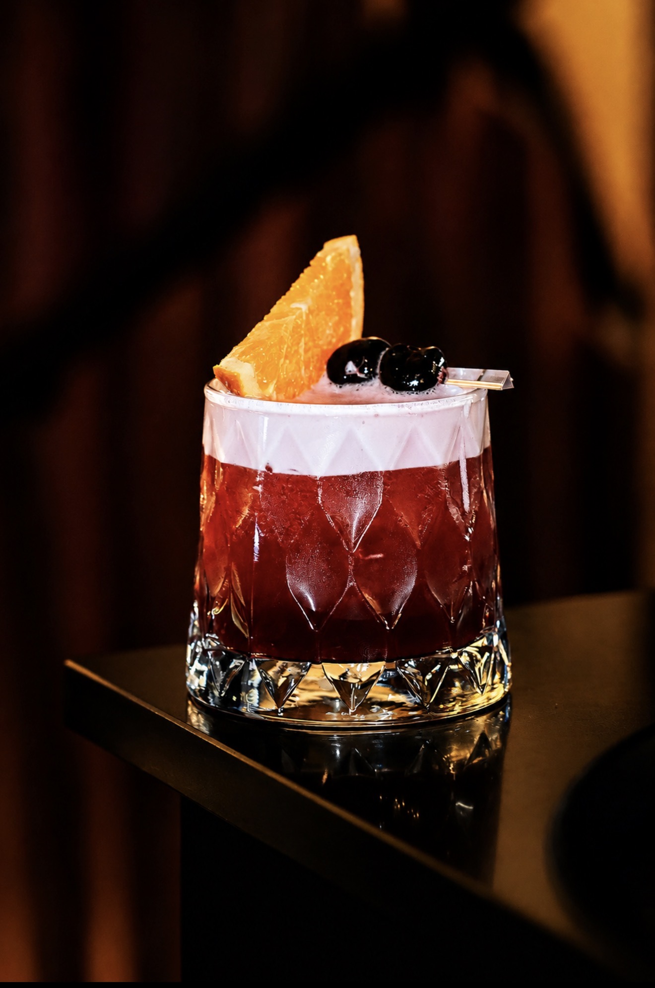 Signature red cocktail with orange garnish, professionally photographed